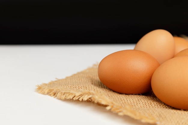 Close up oeufs de poule frais sur nappe en lin et table blanche