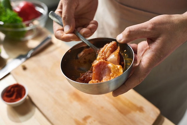 Close-up of cook holding bowl il prépare la viande de poulet avec de la sauce soja