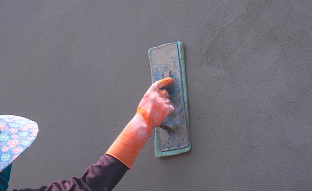 Close up of female Construction Worker main dans un gant en caoutchouc de polissage mur de ciment