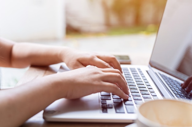 Close-up of freelance people business female casual working with laptop computer with coffee cup and smartphone in coffee shop comme l'arrière-plan