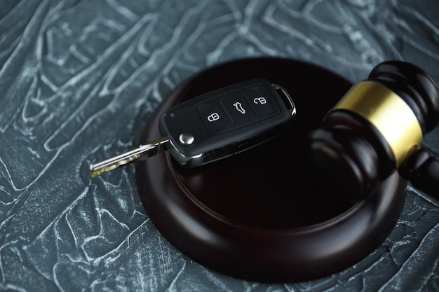 Close-up of Gavel et clé de voiture sur bloc de sondage contre Gray