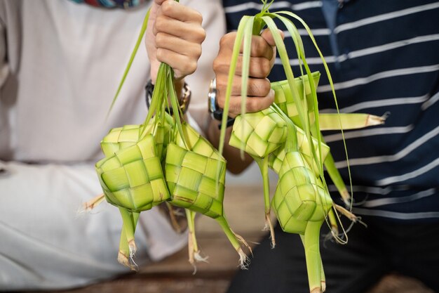 Close up of hand holding ketupat avec feuille de coco