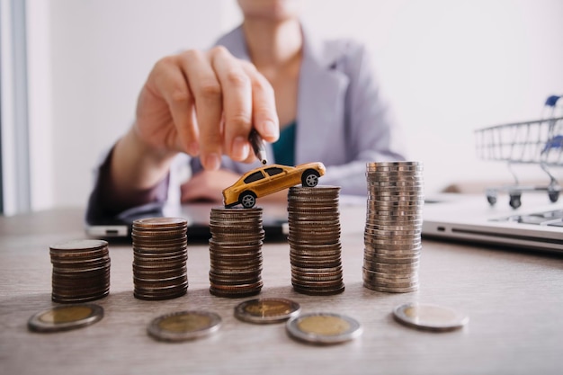 Close up of hand putting coin sur tas de pièces pour économiser de l'argent Recueillir de l'argent pour acheter une nouvelle voiture concept d'épargne et de prêt de voiture Mise à plat