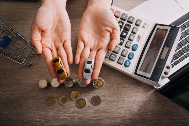 Close up of hand putting coin sur tas de pièces pour économiser de l'argent Recueillir de l'argent pour acheter une nouvelle voiture concept d'épargne et de prêt de voiture Mise à plat