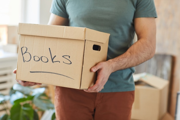 Close-up of man holding boîte en carton avec des livres tout en déplaçant la maison