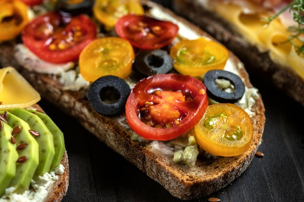 Close up of open sandwich avec tomate cerise rouge et jaune un fond noir