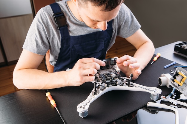 Photo close-up of person's hand repair drone à l'aide d'un tournevis. un homme travaillant dans un atelier de réparation