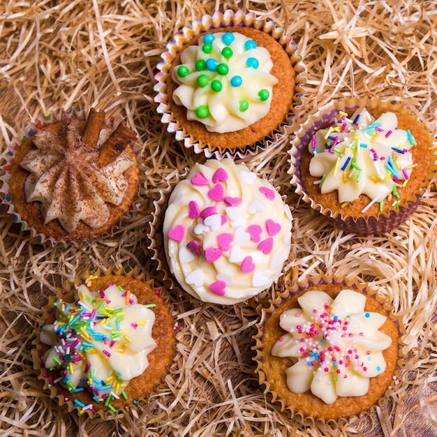 Close up of sweet cupcakes colorés avec de la crème au beurre sur fond de foin