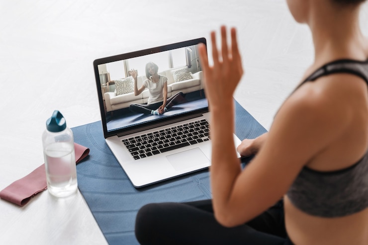 Photo close up of young fit woman coach en sportswear menant une formation de fitness en ligne ou un cours de yoga virtuel sur une vidéoconférence avec ordinateur portable