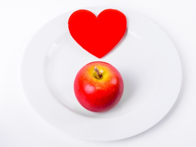 Close up ofCœur rouge avec pomme rouge sur plaque blanche