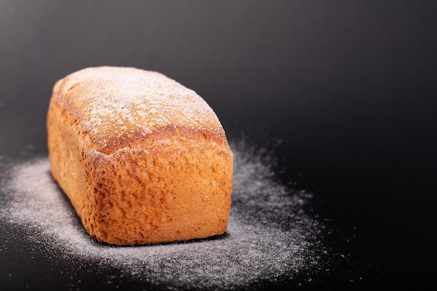 Close up pain maigre français avec de la farine sur un fond noir Concept recette de pain fait main