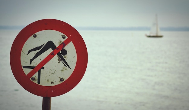 Photo close-up d'un panneau d'avertissement sur route par mer contre le ciel