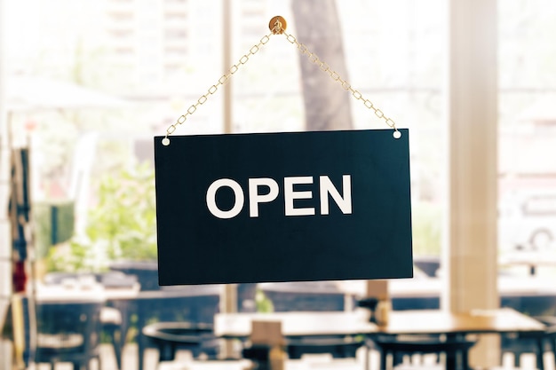 Close-up d'un panneau noir ouvert suspendu à la porte en verre d'un café Arrière-plan flou Concept d'information Rendu 3D