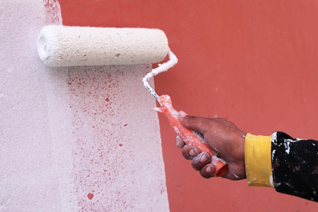 Close-up d'un peintre peignant un mur rouge