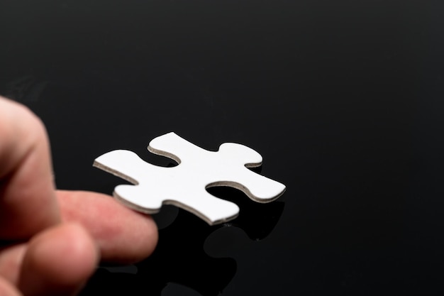 Close-up d'une pièce de puzzle touchée à la main sur un fond noir