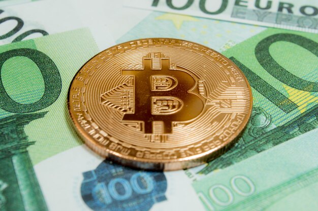 Close-up de pièces Bitcoin sur 100 billets en euros. Crypto-monnaie BTC.