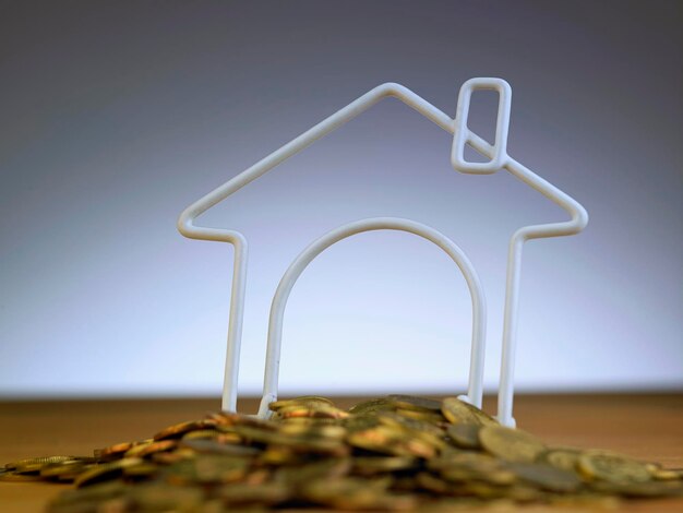 Photo close-up de pièces avec une maison modèle sur table sur un fond gris