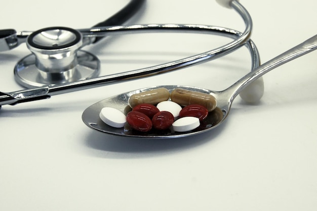 Photo close-up de pilules sur cuillère par stéthoscope sur table