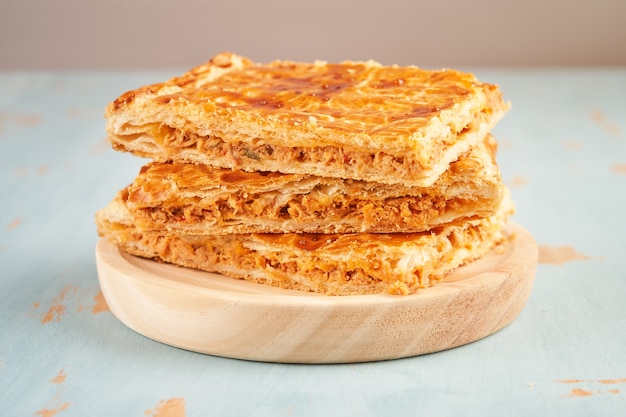 Close up de portions empilées d'une galette farcie au thon sur une plaque en bois