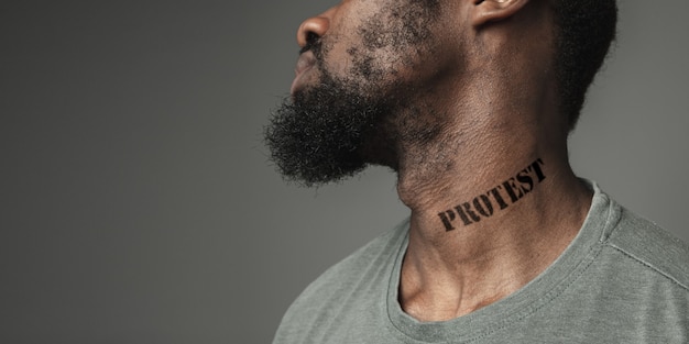 Close up portrait black man fatigué de la discrimination raciale a tatoué un slogan de protestation sur son cou. Concept des droits de l'homme, de l'égalité, de la justice, du problème de la violence et du racisme, de la discrimination. Prospectus.