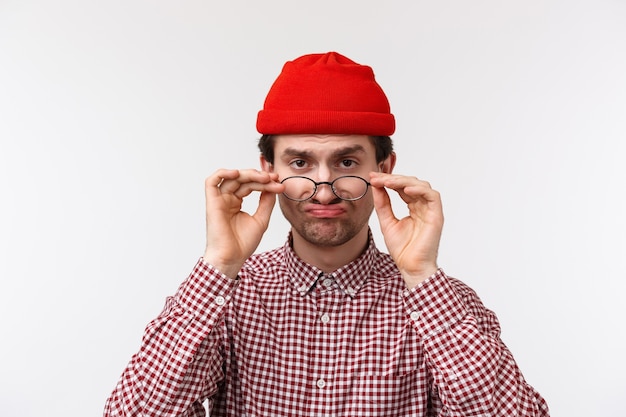 Close-up portrait drôle homme caucasien sceptique en bonnet hipster, regarder sous le front