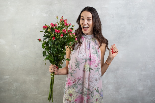 Close-up portrait de jolie jeune femme en robe d'été tenant le bouquet de roses