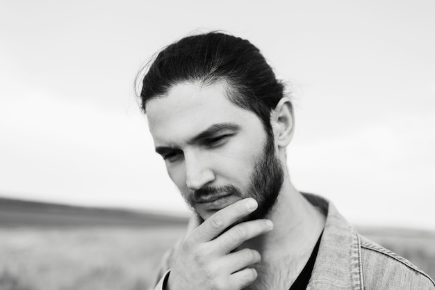 Close-up portrait noir et blanc de jeune homme barbu, sur le terrain.