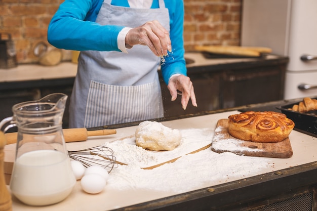 Photo close-up portrait of attractive smiling happy senior age woman is cooking on kitchen. grand-mère faisant une pâtisserie savoureuse.