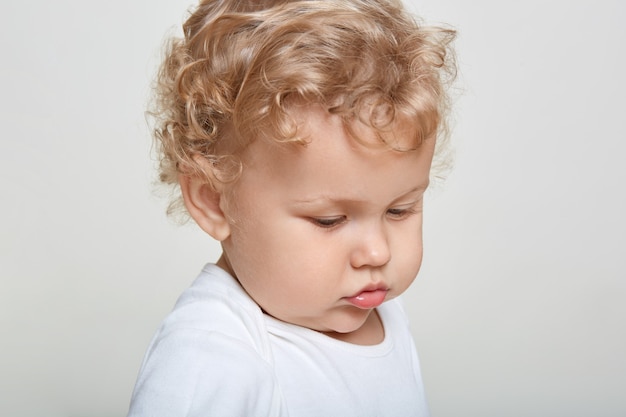 Close up portrait of baby boy looking away, bébé a les cheveux blonds bouclés, portant une chemise décontractée