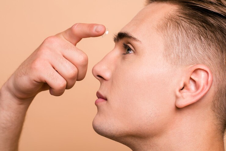 Photo close up portrait of bel homme mettant des lentilles de contact dans son oeil beige isolé