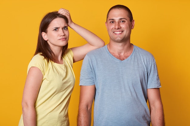 Close up portrait of couple in love, femme insatisfaite garde la main sur l'épaule de l'homme, bel homme se tient souriant