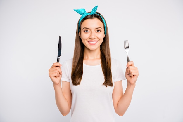 Close-up portrait of nice charmante fille joyeuse joyeuse tenant dans les mains vaisselle couteau fourchette isolé