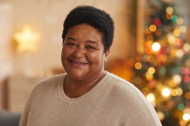 Close up portrait of rire grand-mère afro-américaine regardant la caméra tout en profitant de Noël à la maison, copiez l'espace