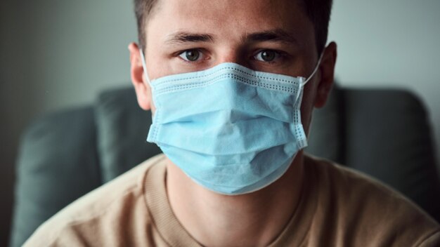 Close-up portrait of young man wearing medical mask