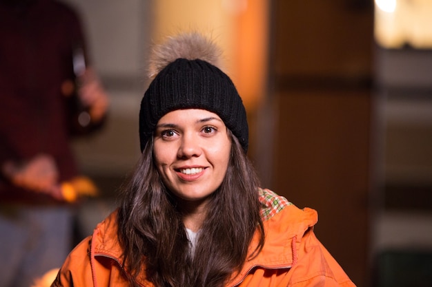 Close up portrait of young woman smiling avec camping-car rétro en arrière-plan. Feu de camp.