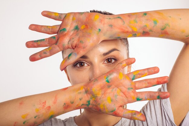 Photo close-up portrait teenage girl couvre son visage avec ses paumes dans la peinture isolé sur blanc