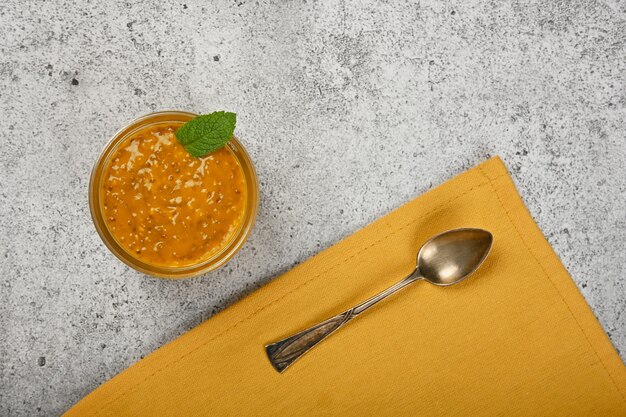 Close up un pot en verre transparent de pudding de graines de chia dessert avec mangue sur table, vue de dessus, directement au-dessus