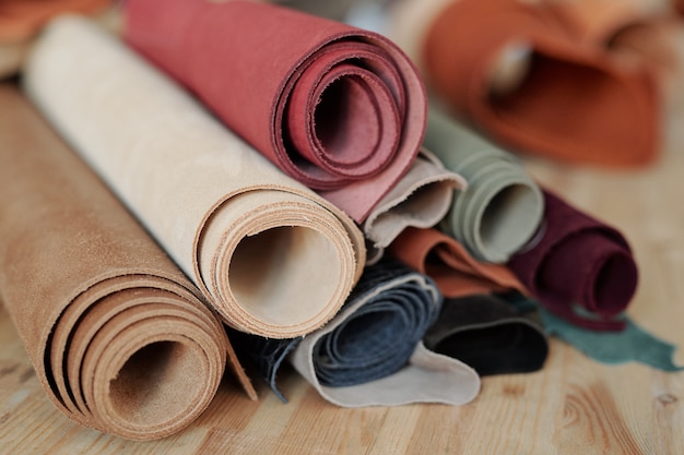 Close-up de rouleaux de cuir colorés empilement sur table en bois en atelier