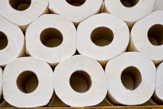 Close up rouleaux de papier toilette sur une étagère en bois dans une salle de bains.