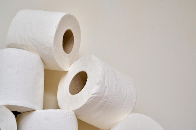 Close up rouleaux de papier toilette sur une étagère en bois dans une salle de bains.