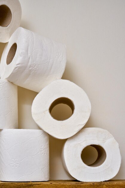 Close up rouleaux de papier toilette sur une étagère en bois dans une salle de bains.