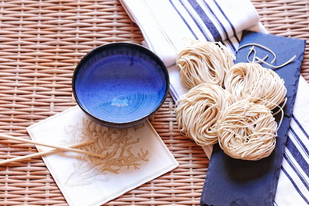 Photo close-up de spaghettis crus avec un bol et des baguettes sur la table