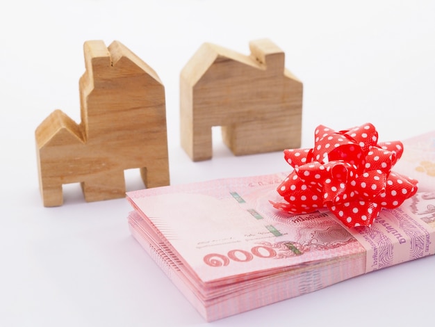 Close Up Tas De Billets Avec Arc Rouge Et Modèle De Maison En Bois Sur Fond Blanc