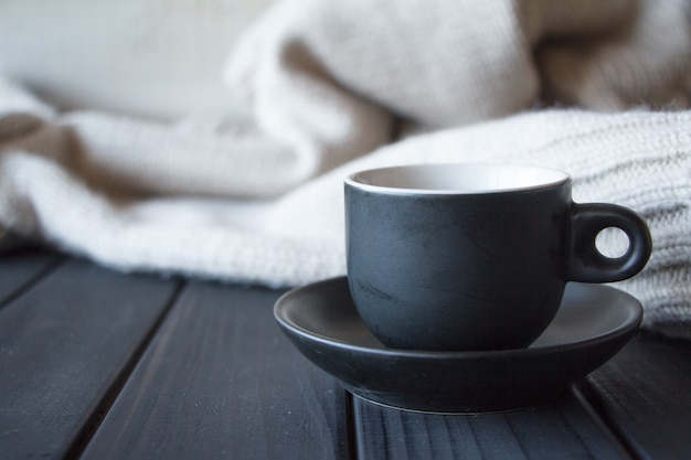 Close-up tasse noire avec café sur pull gris en texture de laine naturelle