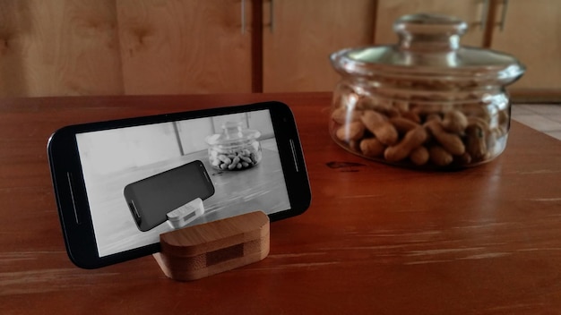 Close-up d'un téléphone intelligent par de la nourriture dans un pot en verre sur une table en bois