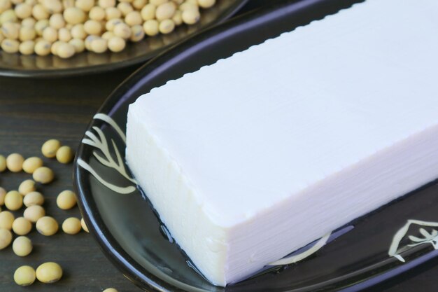 Photo close-up d'un tofu doux avec une pile de soja séché floue en arrière-plan