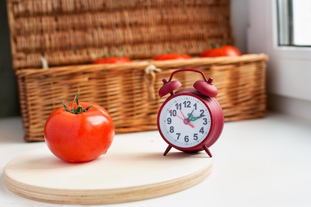 Photo close-up d'une tomate par un réveil sur la table