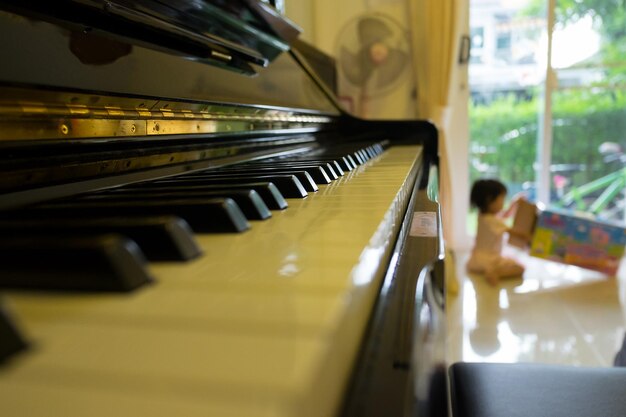 Photo close-up de touches de piano avec un enfant jouant en arrière-plan à la maison