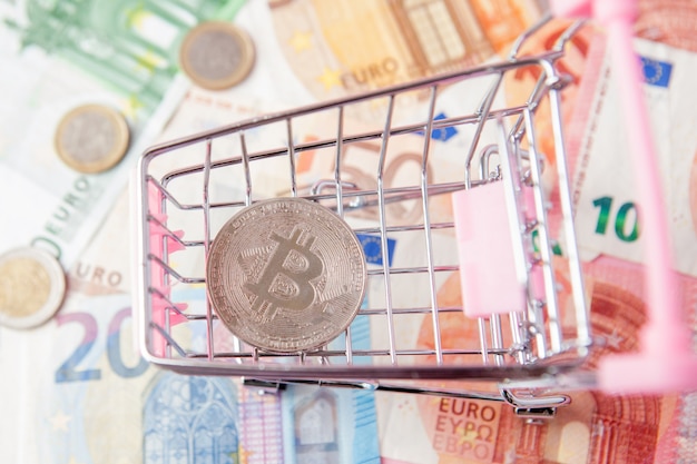 Close up toy shopping cart avec bitcoin sur les billets en euros