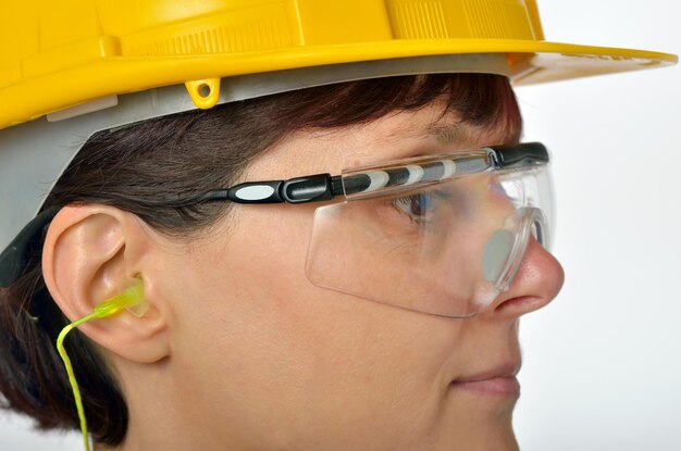 Photo close-up d'une travailleuse manuelle portant des lunettes de protection sur un fond blanc